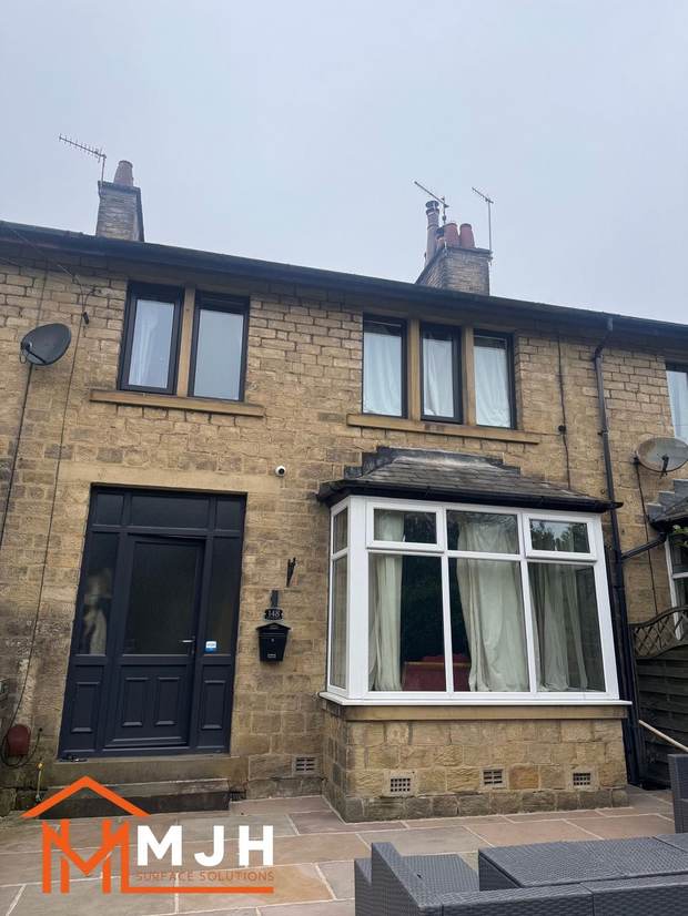 Stone terraced house before spraying, with a white uPVC bay window